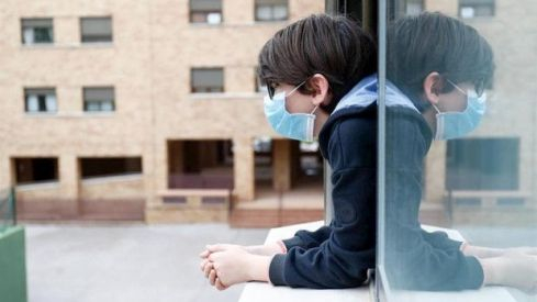ep_un_nino_con_una_mascarilla_se_asoma_a_la_ventana_de_su_casa_durante_el_confinamiento_620x350