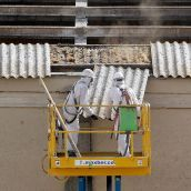 Dos trabajadores retiran placas de uralita con amianto en el tejado de una nave industrial de Arroyo de la Encomienda (Valladolid)