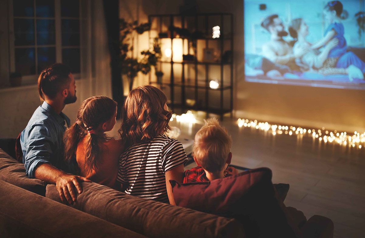 family mother father and children watching projector, TV, movies with popcorn in   evening   at home