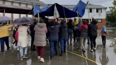 Una lona sirve de techo móvil a los niños del colegio de Columbrianos para disfrutar del recreo a pesar de la lluvia