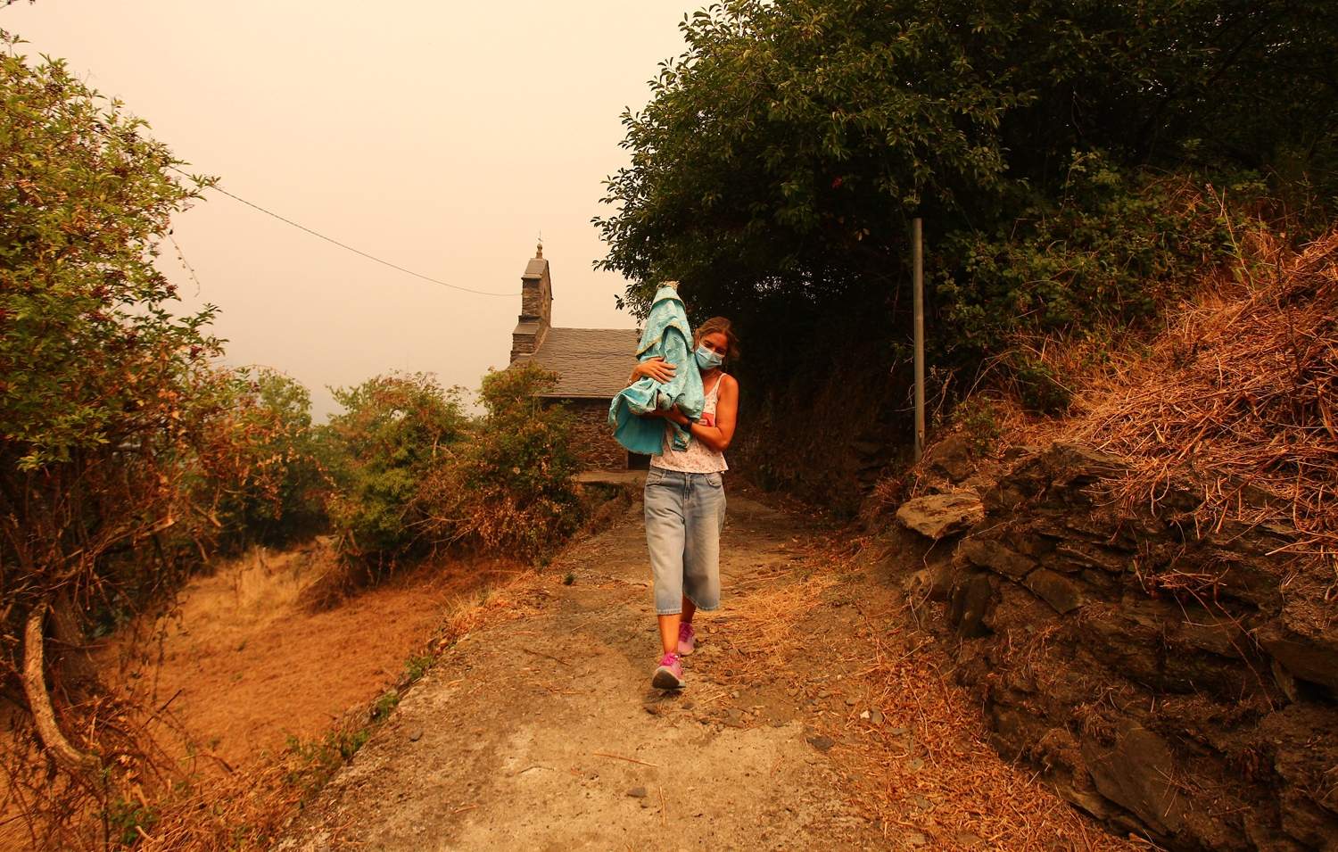 César Hornija / ICAL. Una vecina de Lusio (Oencia), rescata la Santa del pueblo ante la posible llegada del fuego