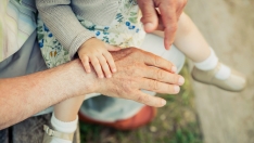 Bebé tocando la mano de un anciano | iStock: doble d Bebé tocando la mano de un anciano | iStock: doble d