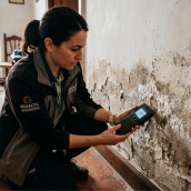 Técnico especialista midiendo el nivel de humedad en la base de un muro con higrómetro de contacto, paso previo al diagnóstico diferencial.