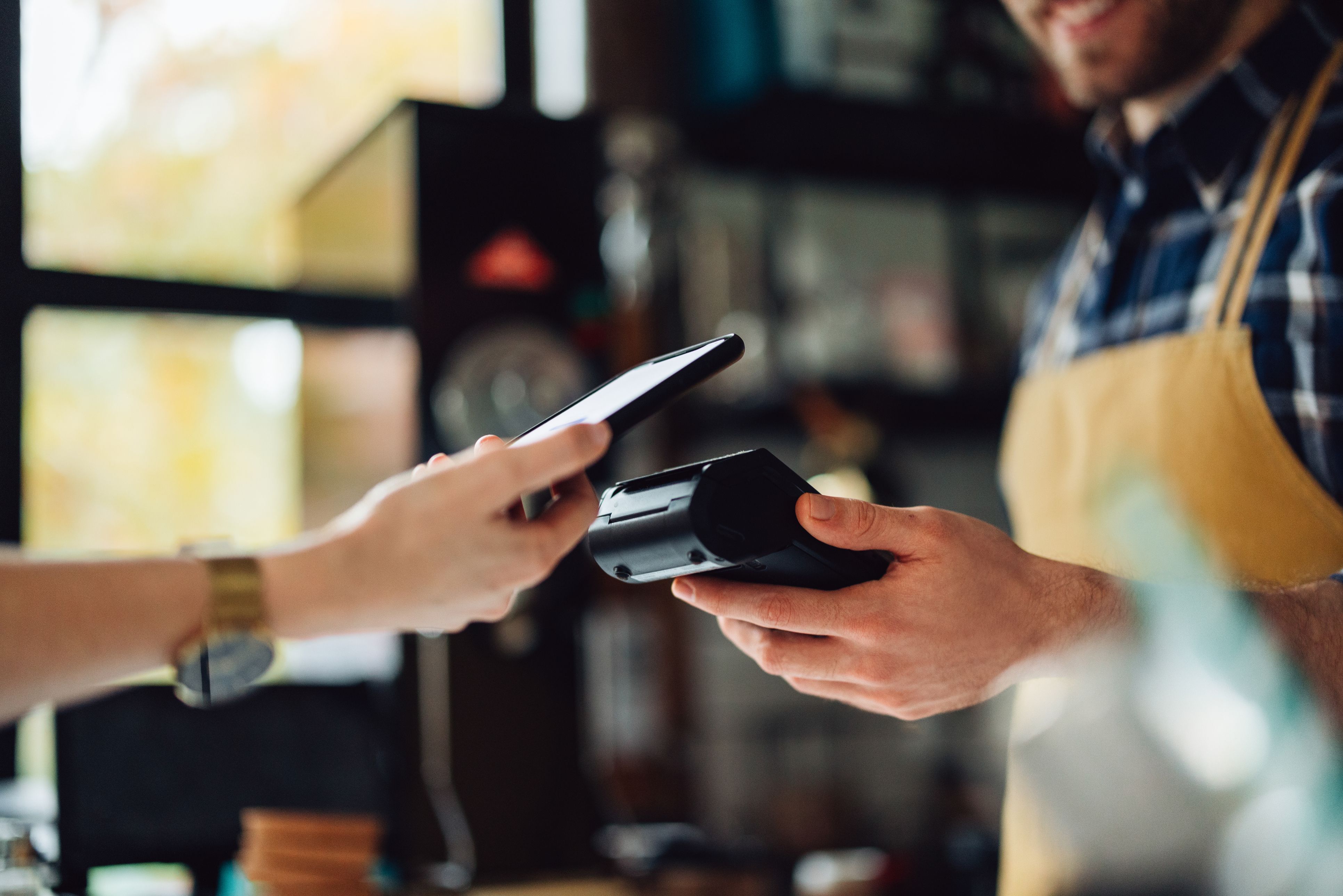 Persona pagando en un establecimiento con el móvil | iStock autor: miniseries