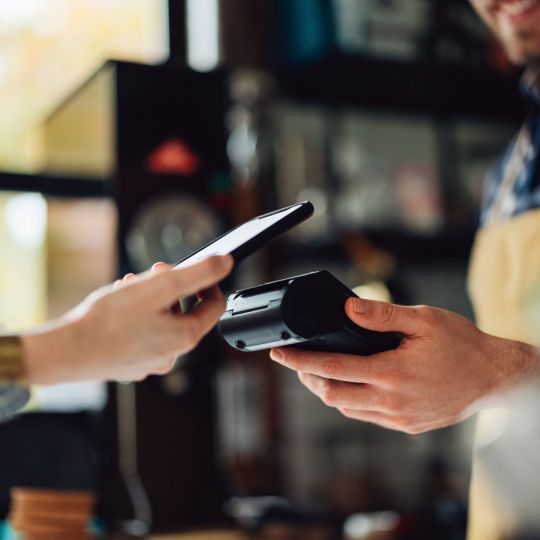 Persona pagando en un establecimiento con el móvil | iStock autor: miniseries