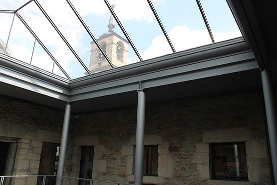 En la ventana de la derecha la antigua maquinaria despojada del reloj, con la torre al fondo